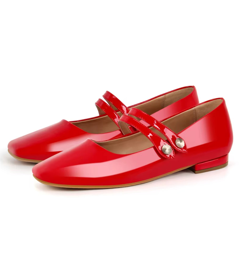 Pair of red patent leather shoes with a strap on a white background