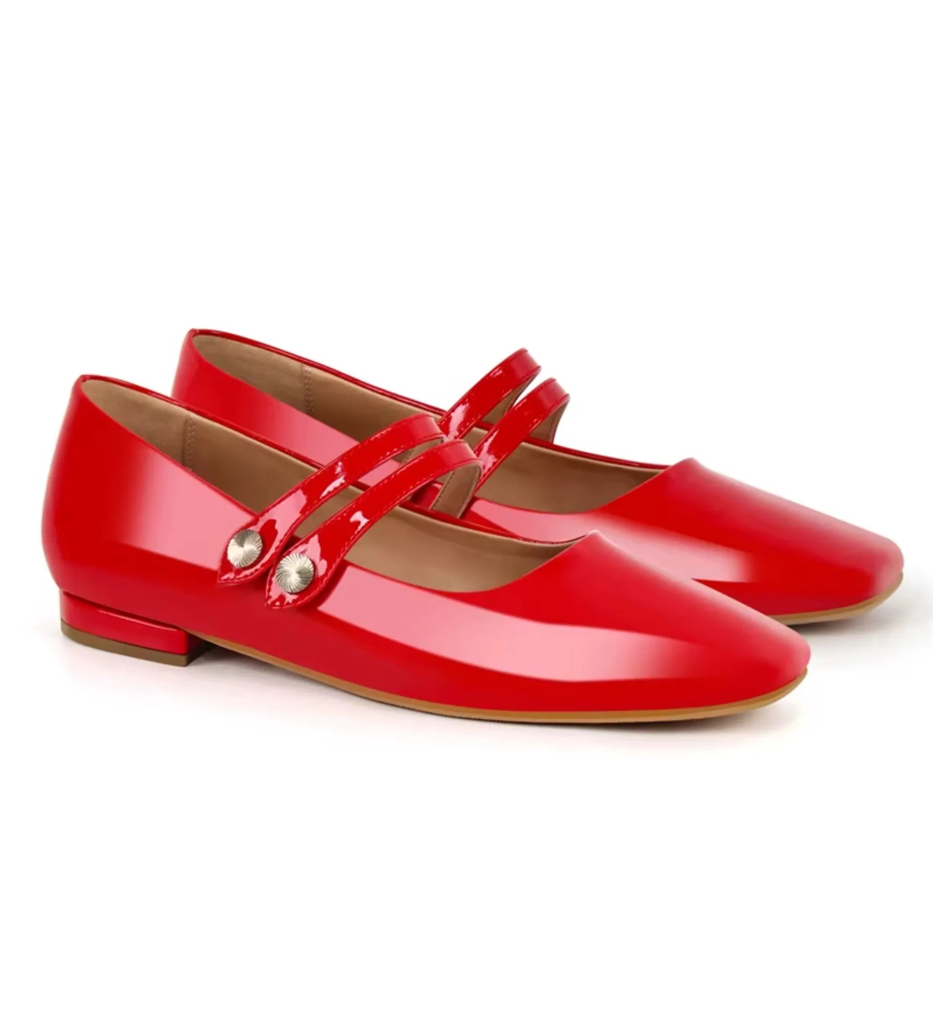 Pair of red patent leather shoes with straps on a white background