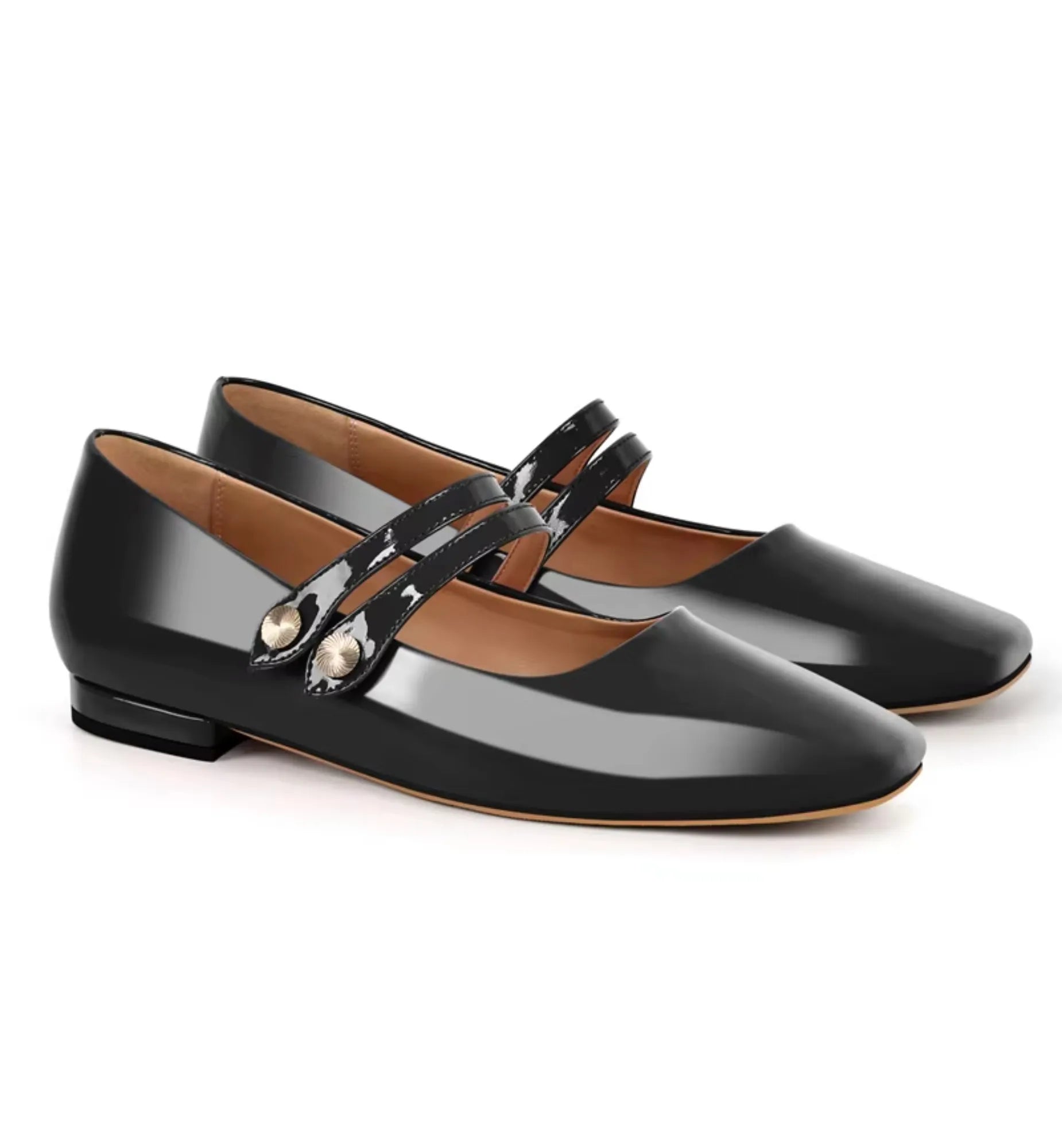 Pair of black patent leather shoes with a strap on a white background