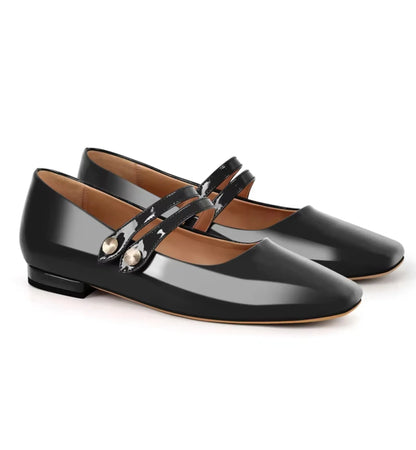 Pair of black patent leather shoes with a strap on a white background