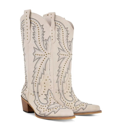 Pair of white cowboy boots with intricate designs on a white background