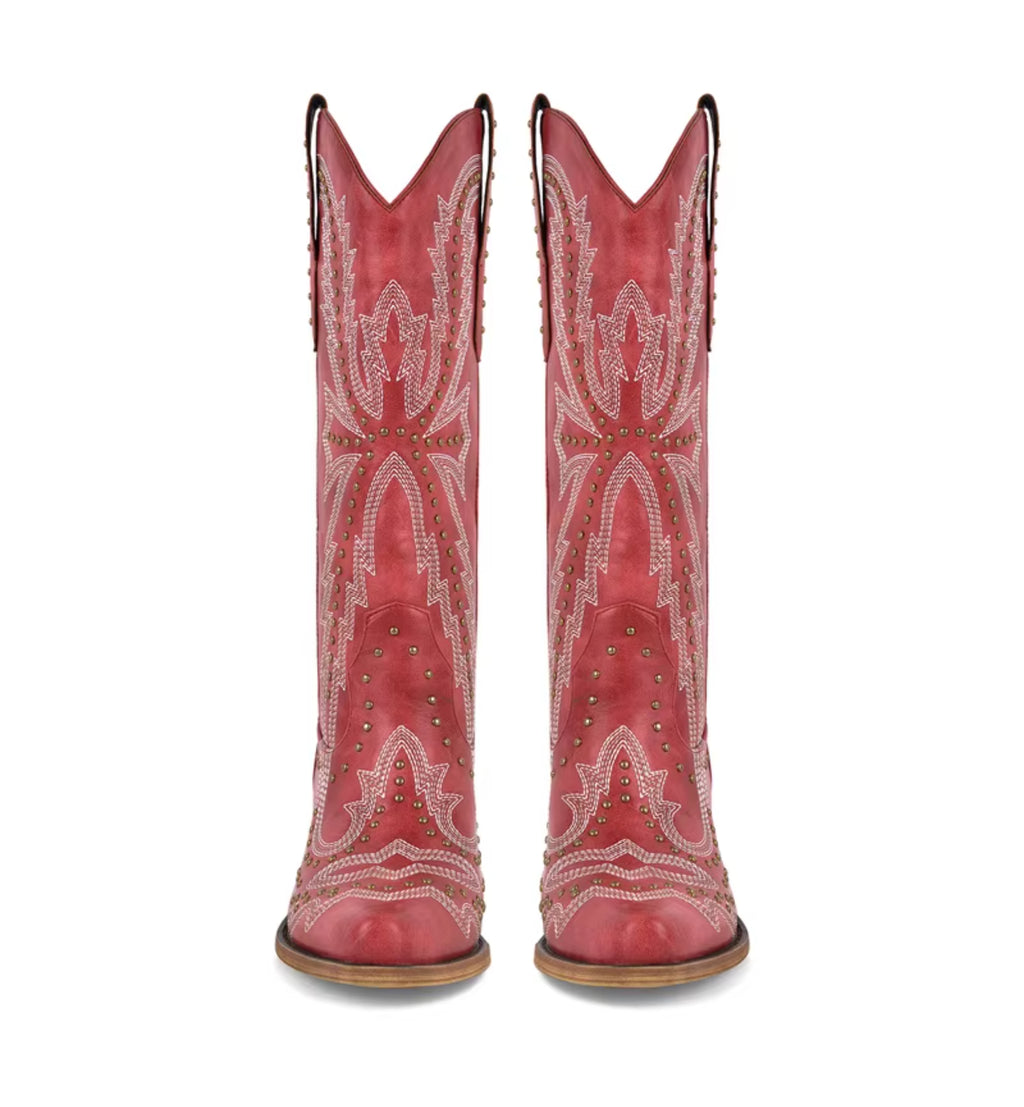 Red cowboy boots with white embroidery and studded details on a white background