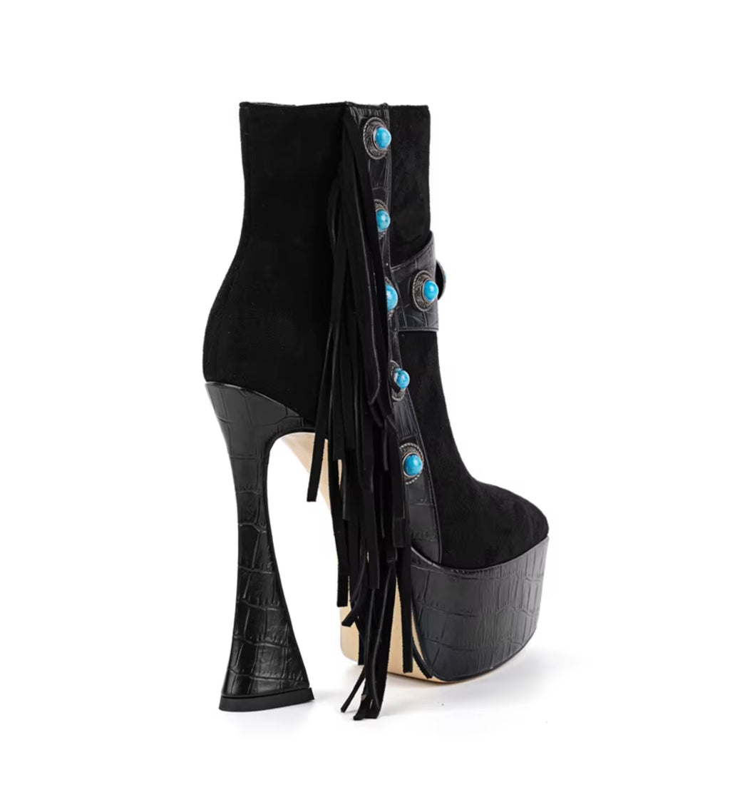Black high-heeled platform boots with turquoise buttons and fringes on a white background
