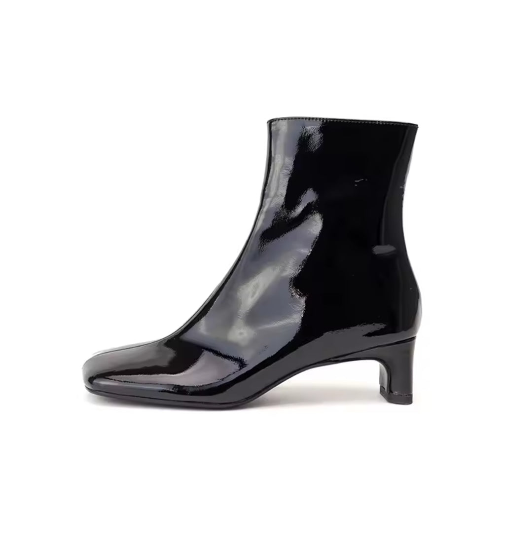 Black patent leather ankle boot on a white background