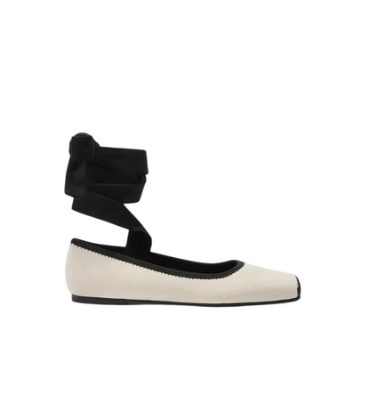White flat shoe with black ankle strap on a white background