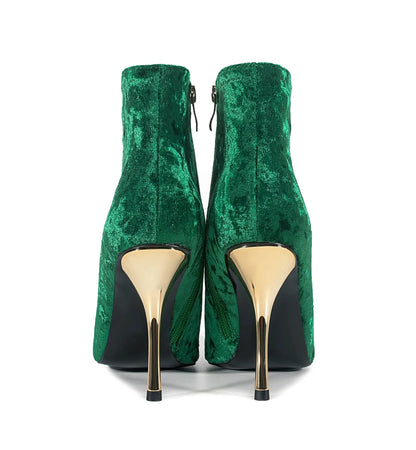 Green velvet high-heeled shoes with gold soles on a white background