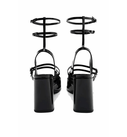 Black high-heeled shoes with unique strap design on a white background